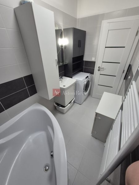 Bathroom with a bathtub, washing machine, and storage cabinets in a 3-room apartment.