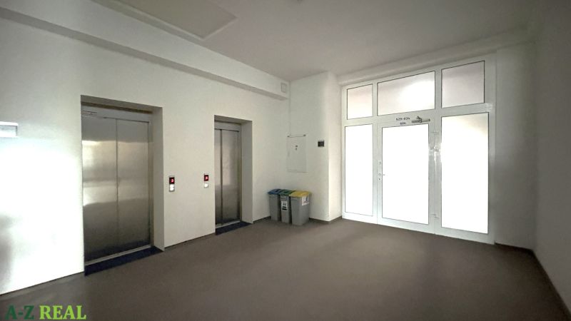 Offices with two elevators and recycling bins, floor with wood decor.