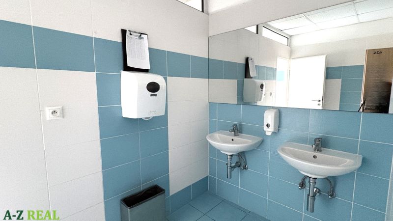 Bathroom in offices with white and blue tiles, sinks, and a mirror.