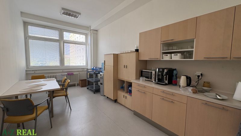 Office interior with kitchenette, table, chairs, and a vending machine.