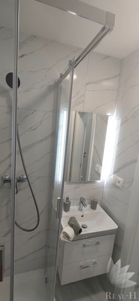 A bathroom in a 3-room apartment with marble tiles and a shower corner.