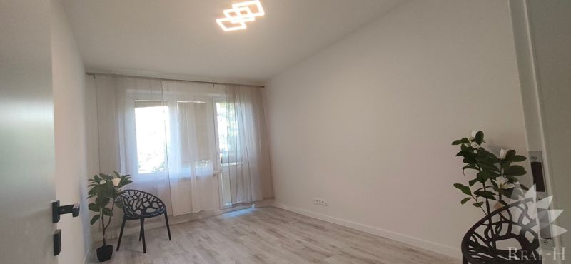 A bright room in a 3-room apartment with a wooden decor floor and plants.