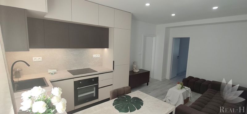 A kitchen in a 3-room apartment with a modern kitchen unit and wood decor.