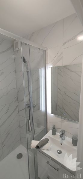 A bathroom with marble-look tiles and a shower in a 3-room apartment.
