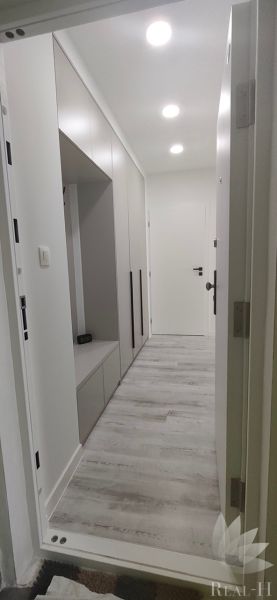 A bright hallway in a 3-room apartment with storage cabinets and a wooden decor floor.