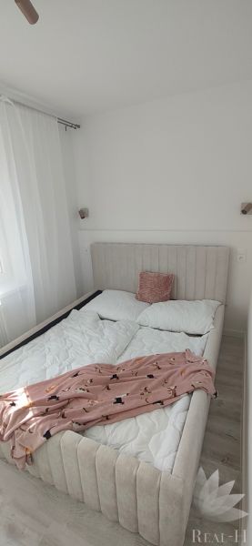 Bedroom in a 3-room apartment with a bed, light curtains, and a floor with a wooden decor.