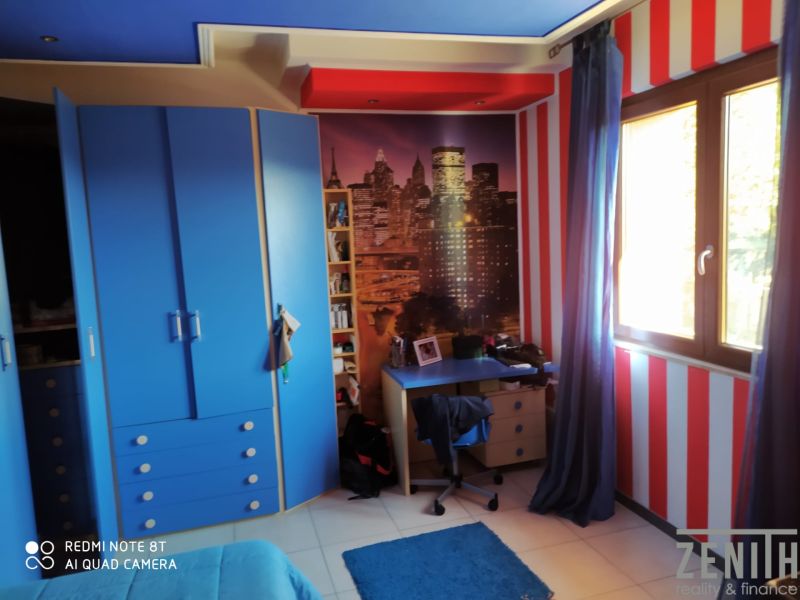 A room in a villa with blue furniture, red stripes, and a poster of a city skyline.