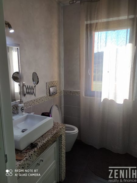 Bathroom in the villa with a sink, toilet, and a window with a curtain.