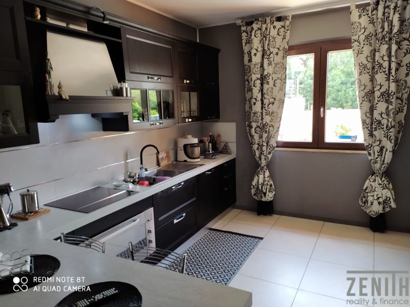 A kitchen in a villa with dark cabinets, a window, and patterned curtains.