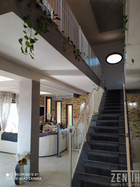 Interior of a villa with a spacious staircase, flowers, and a comfortable living area.