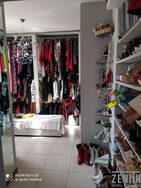 Wardrobe in the Villa with a variety of clothes, shoes, and accessories on the shelves.