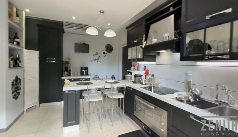 A kitchen in a villa with elegant black cabinets, a bar counter, and modern appliances.