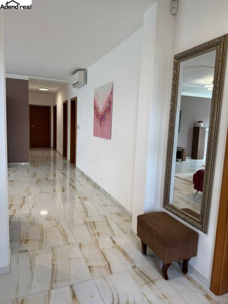 A hallway in a family house with a shiny floor, a large mirror, and wall decorations.