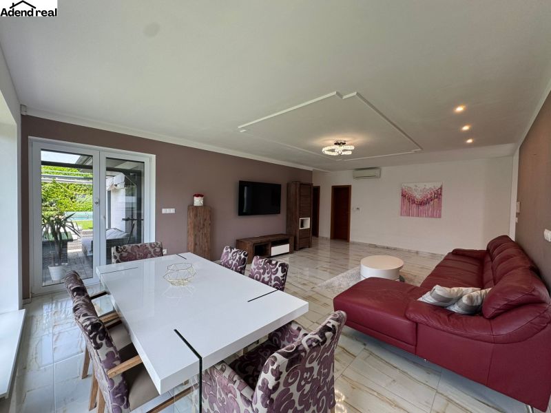 Living room of a family house with a red sofa and a white dining table.