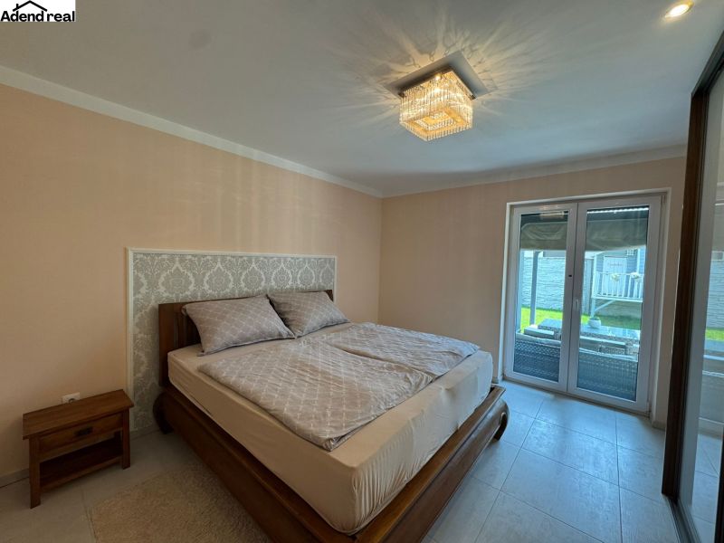 Bedroom in a family house, bed with a decorative headboard and sliding glass doors.