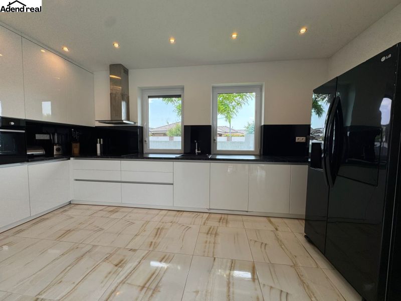 A kitchen with black and white cabinets, a black refrigerator, and ceramic flooring.