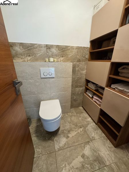 Bathroom in a family house with a toilet, tiles, and storage space for towels.