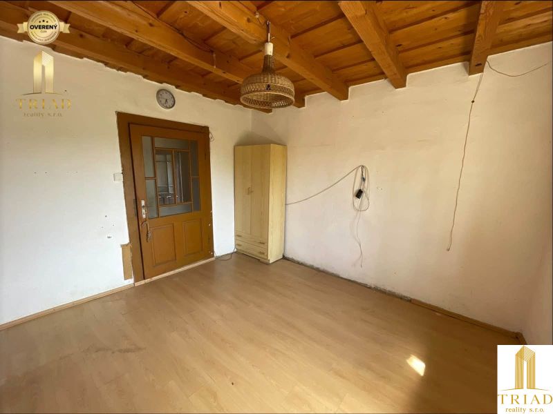 The interior of a cabin with a wood-patterned floor, a wardrobe, and a chandelier.