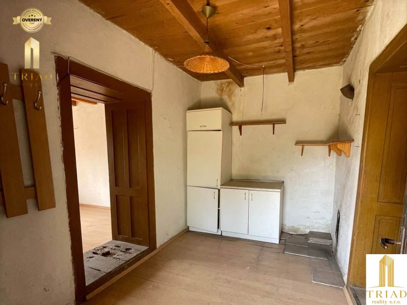 A kitchenette in a cottage with white cabinets and wooden decor on the floor.