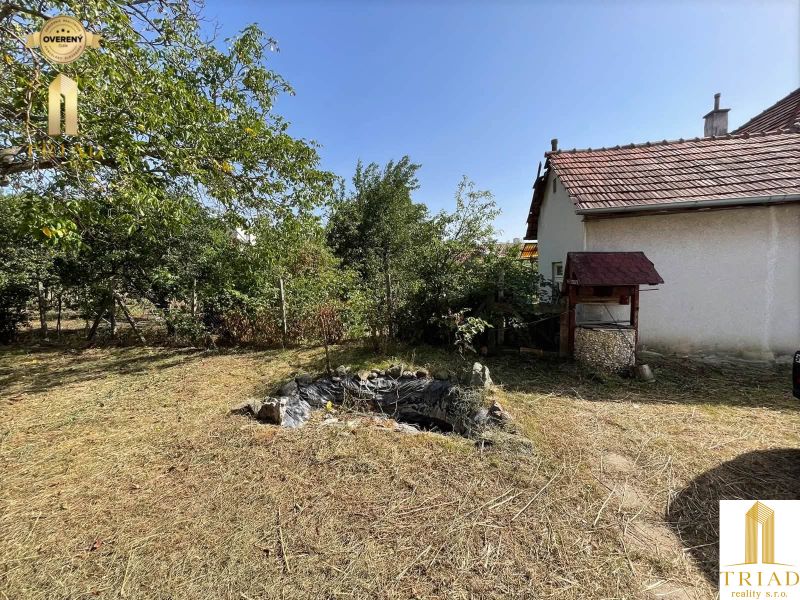 Garden area by the cottage in Čaka with a wooden well and maintained lawn.