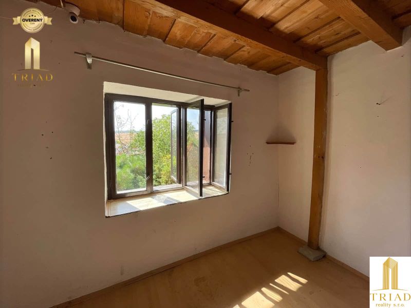 A room with wooden decor, a wooden panel ceiling, and a window with a view of greenery.
