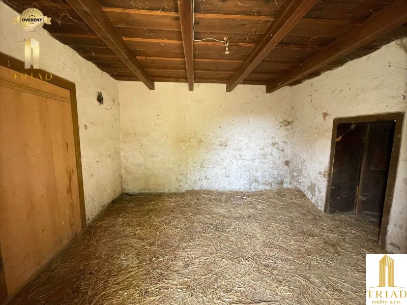 A room with a straw floor and a wooden ceiling in a cabin.