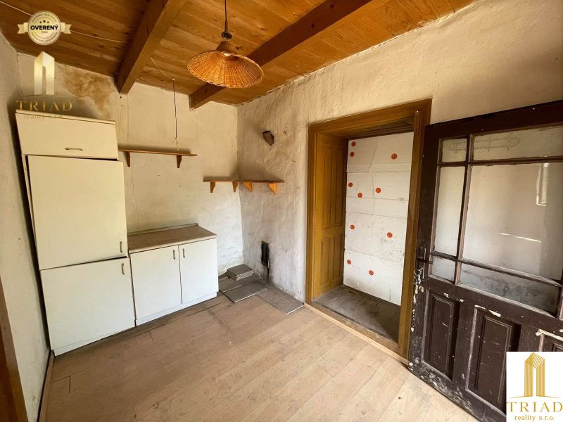 The interior of the cottage with a wood-decorated floor, older furniture, wooden ceiling, glass doors.