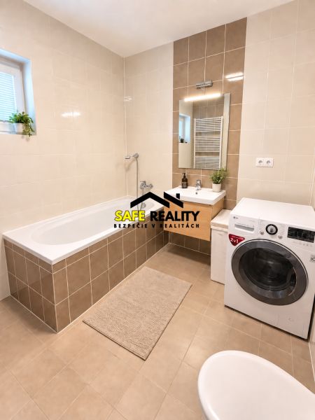 Bathroom with a bathtub, washing machine, and sink in a 2-room apartment.