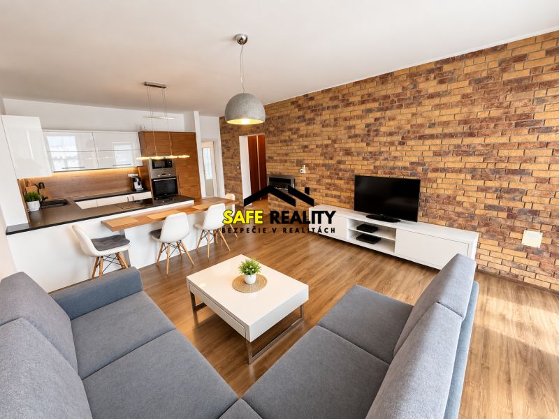 Living room of a two-room apartment with a wooden decor floor and a brick wall.