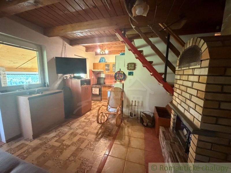 The interior of a cabin with a fireplace, a wooden decor floor, and a wooden ceiling.