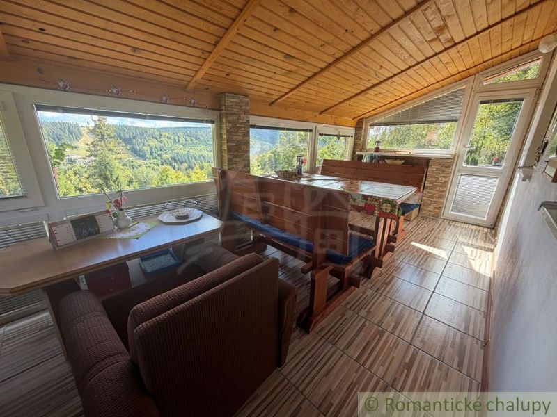 Dining corner in a cottage with a view of green hills and forests.