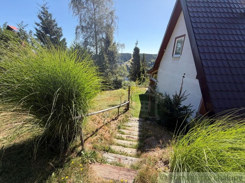 A cottage in Látky with wooden stairs and a view of green hills.