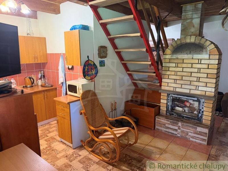 A kitchen corner in a cabin with a fireplace and stairs, floor with wooden decor.
