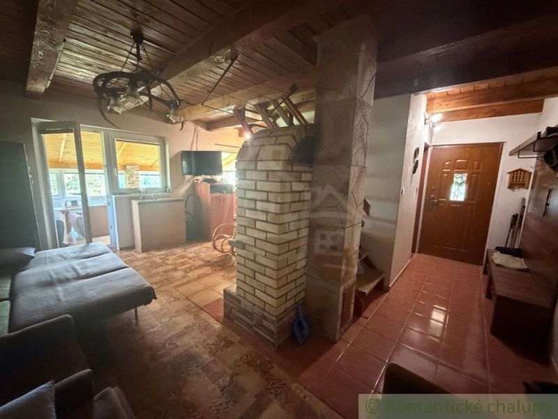 Interior of a cabin with a wooden decor floor, fireplace, and entrance door.