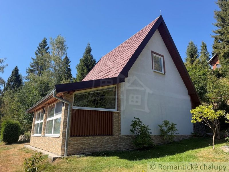 A cottage in Látky, surrounded by greenery and forest, in beautiful sunny weather.