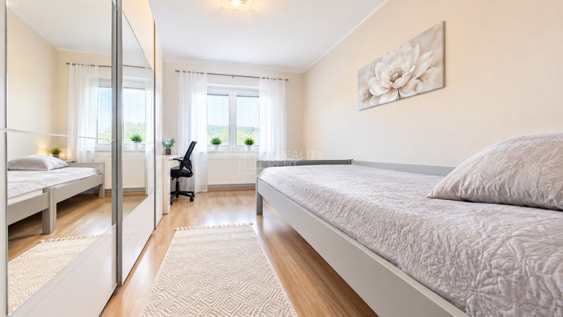 Bedroom in a family house with wood-patterned flooring, a mirrored wardrobe, and a writing desk.