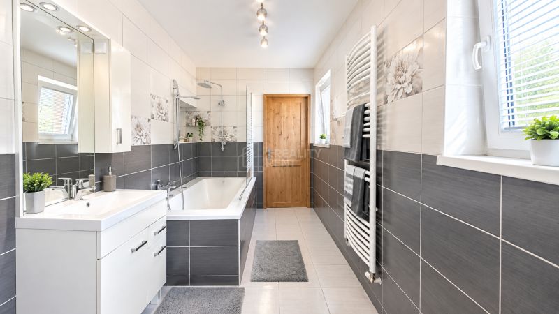 A bathroom in a family house with a bathtub, modern tiles, and wall decorations.