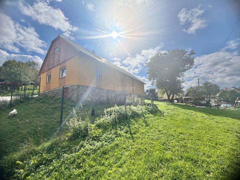 A family house in Košariská in Oščadnica surrounded by a green lawn and trees.