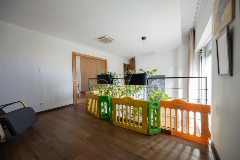 Interior with railing, playpen, hanging flower pots, and floor with wooden decor.