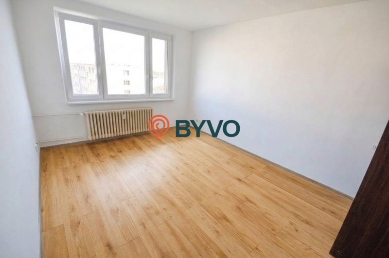 A room in a 2-room apartment with a large window and a floor with a wooden decor.