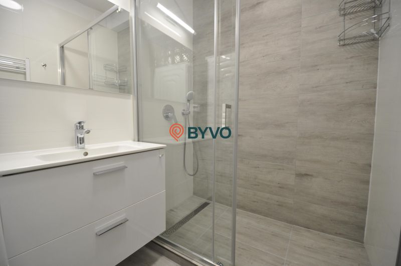 A bathroom with a shower and a sink in a 2-room apartment.