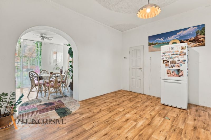 A family house with a wooden decor floor, a dining table, and a refrigerator.