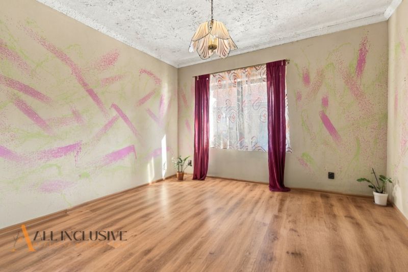 Interior of a family house with a wooden decor floor, colorful wall, and curtains.