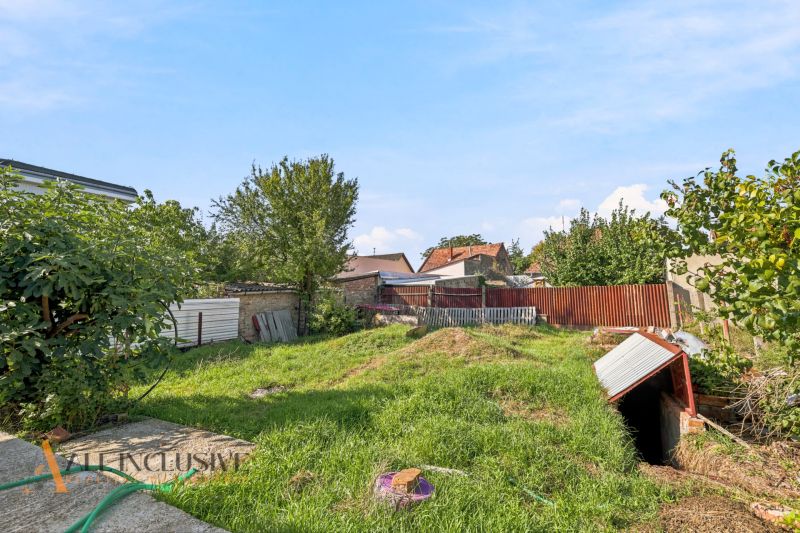 A garden at a family house in Komárno with a lawn and a wooden fence.