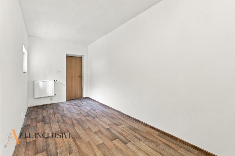 A room in a family house with a wooden decor floor and a simple radiator.