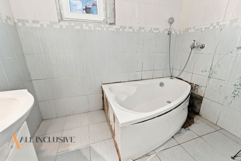 A bathroom with a corner bathtub and white tiles in a family house.