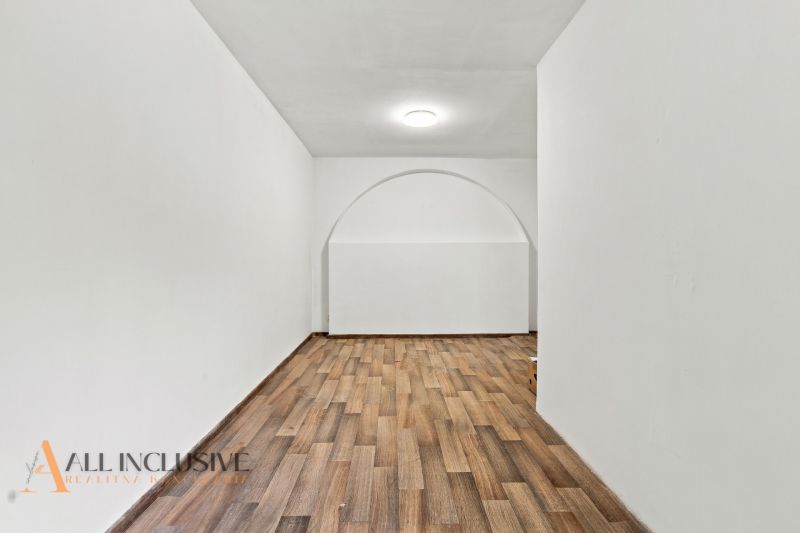 A room in a family house with a wooden decor floor and an arched passageway.