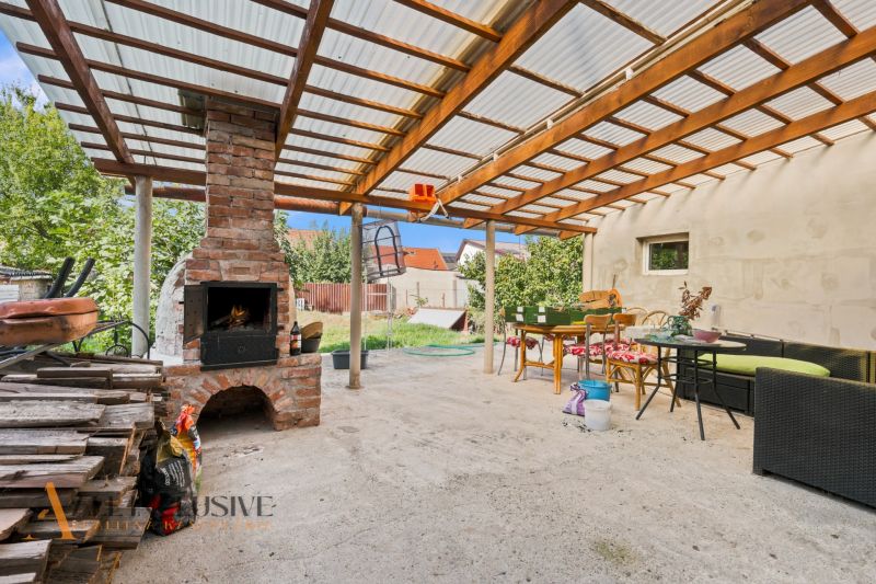 Garden terrace with a brick fireplace in a family house in Komárno, under a pergola.