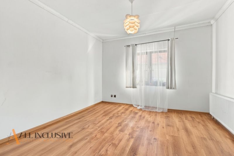 White room with a large window and a wood-patterned floor in a family house.