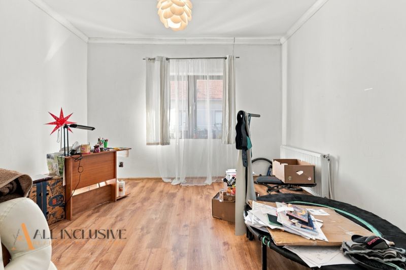 A room in a family house with a wooden decor floor, a table, a window, and decorations.